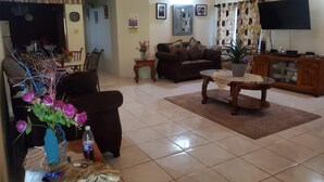 A living room with a sofa, coffee table, TV, and decorative items. - Sun Valley Retreat in Montego Bay (Montego Bay)