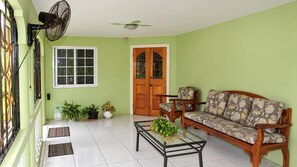 A room with a sofa, a coffee table, a fan, a door, and potted plants. - Montego Bay 3-bed Home, Sleeps 6 Parking & Garden (Montego Bay)