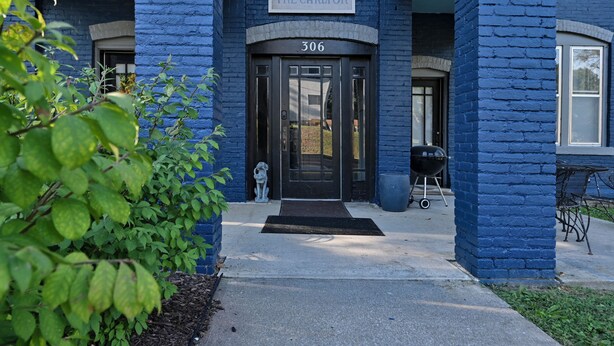 A blue brick building with a sign reading "THE CARLTON" and the number "306" above the entrance. - Dual patios, Free Laundry Service, College steps, 2BR 1 BA (Atchison)