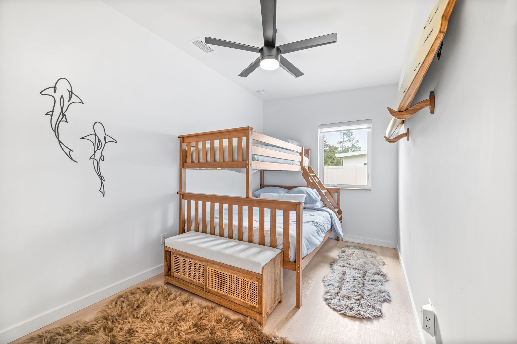A bedroom with a bunk bed, a ceiling fan, a small window, and a wall-mounted shelf.