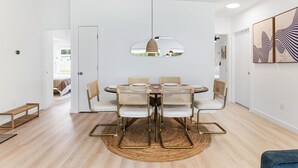A dining area with a round table, six chairs, and a hanging pendant light.