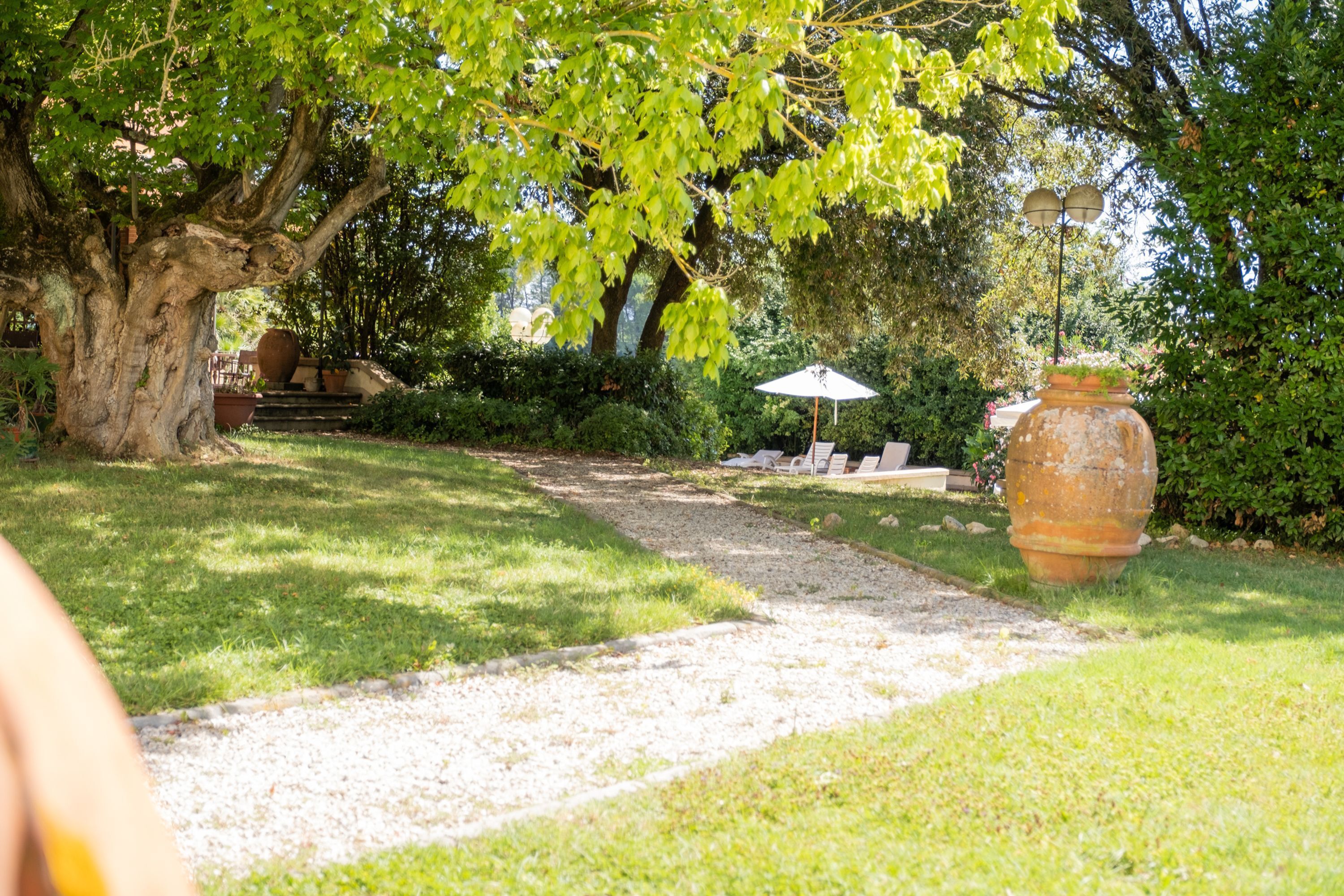 Un sentier de jardin qui mène à un espace de détente en plein air, aménagé sous un arbre.