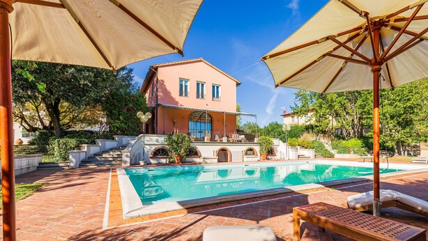 Ein Poolbereich mit Pool, Liegestühlen und Sonnenschirmen.