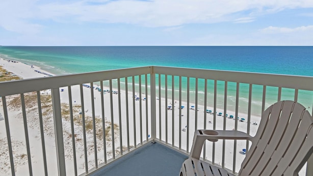 Un balcon avec vue sur une plage et l’océan.