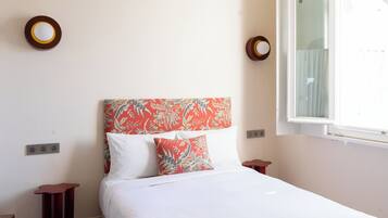 Un dormitorio con cama, ventana e enchufe.