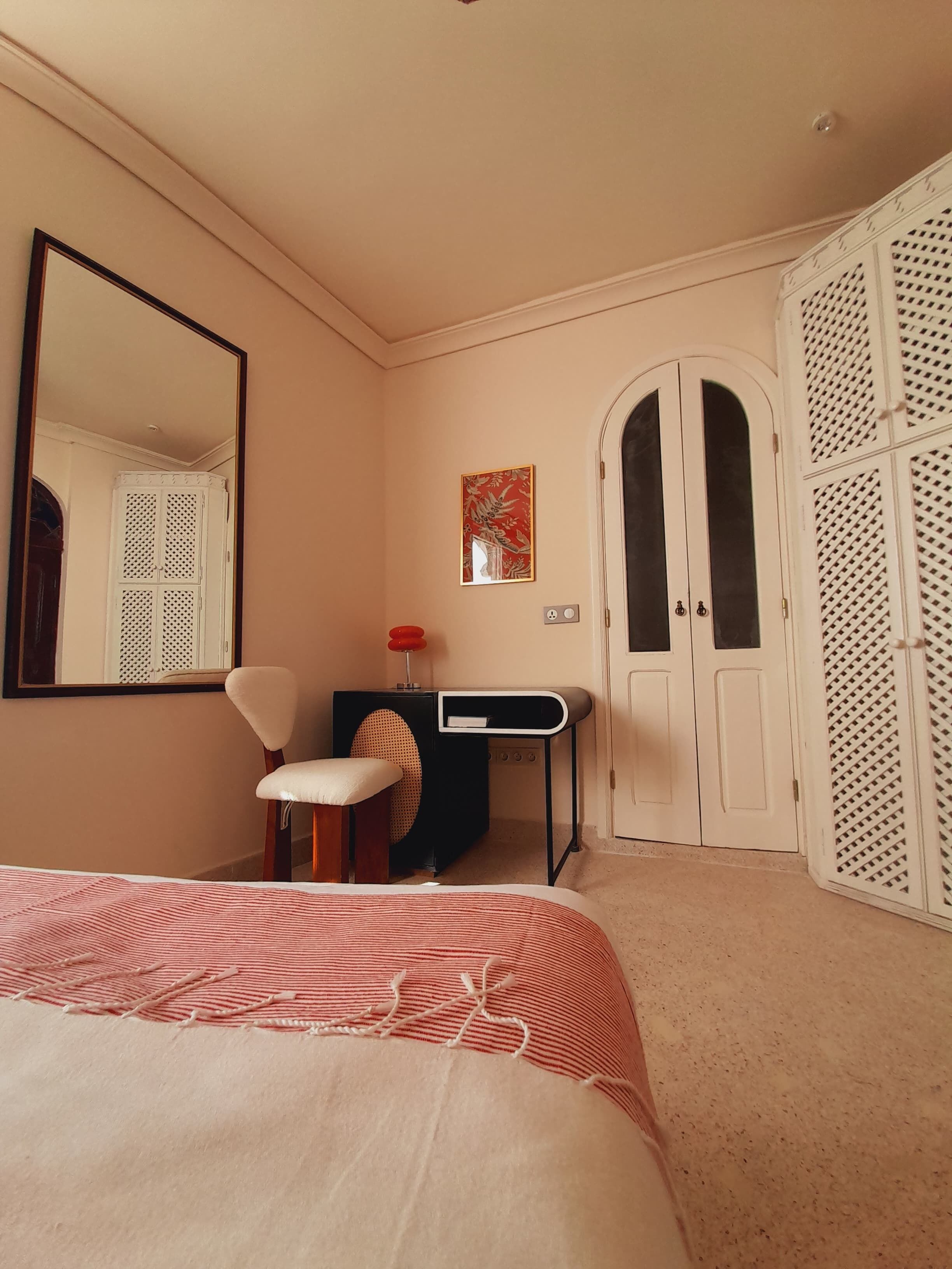 A bedroom with a bed, a desk, a chair, a wardrobe, and a mirror.