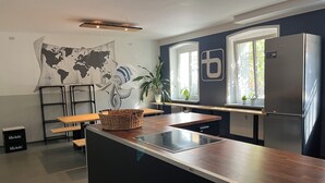 A modern kitchen with a large island, a world map mural, and a refrigerator. - Blue Doors Hostel Altstadt (Rostock)