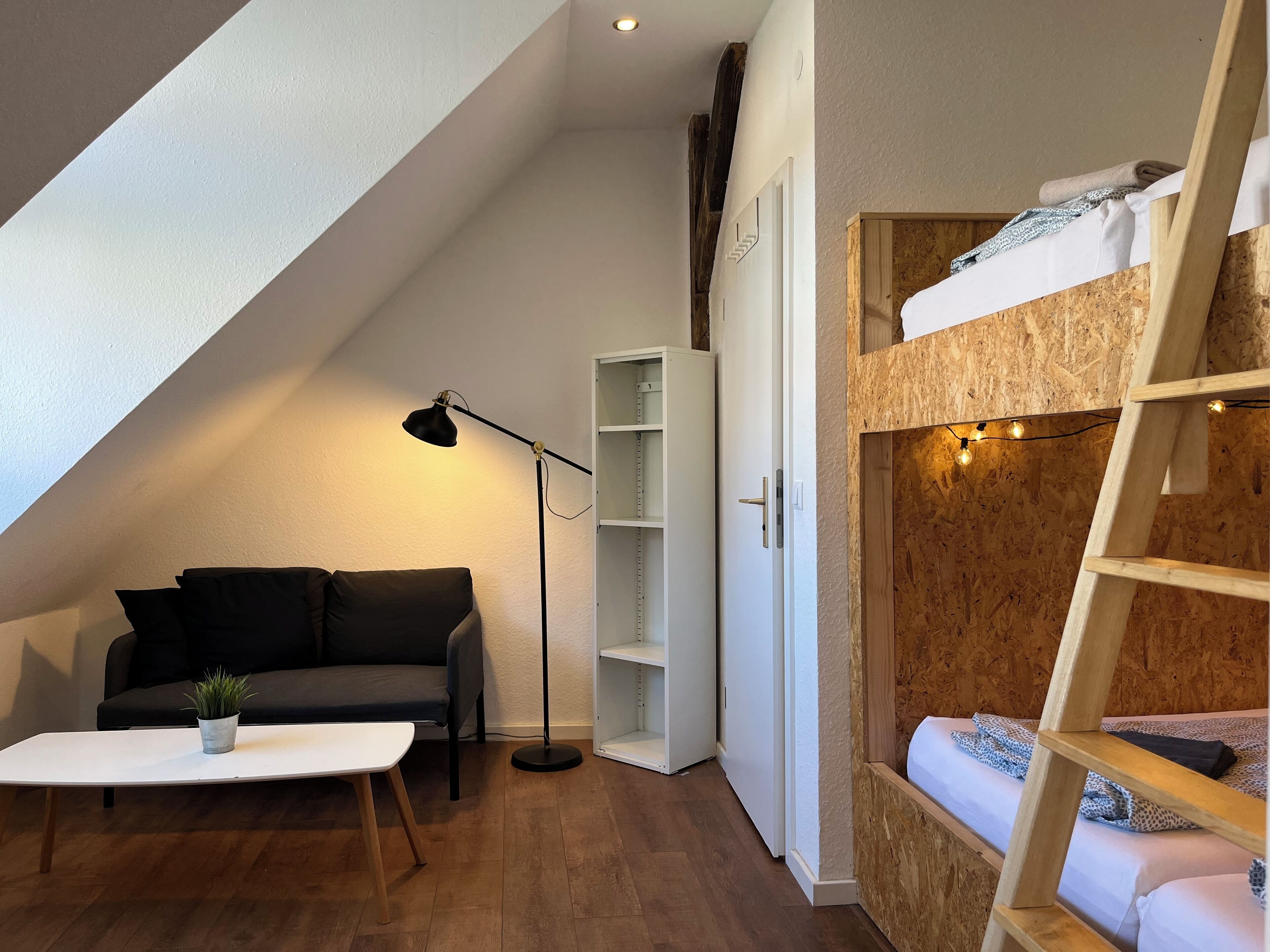 Ein kompakter Wohnbereich mit Schlafkoje, Sofa, Couchtisch und Stehlampe.