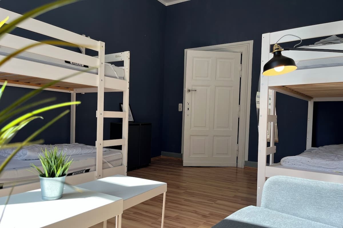 A room with bunk beds, a desk, a chair, and a door.