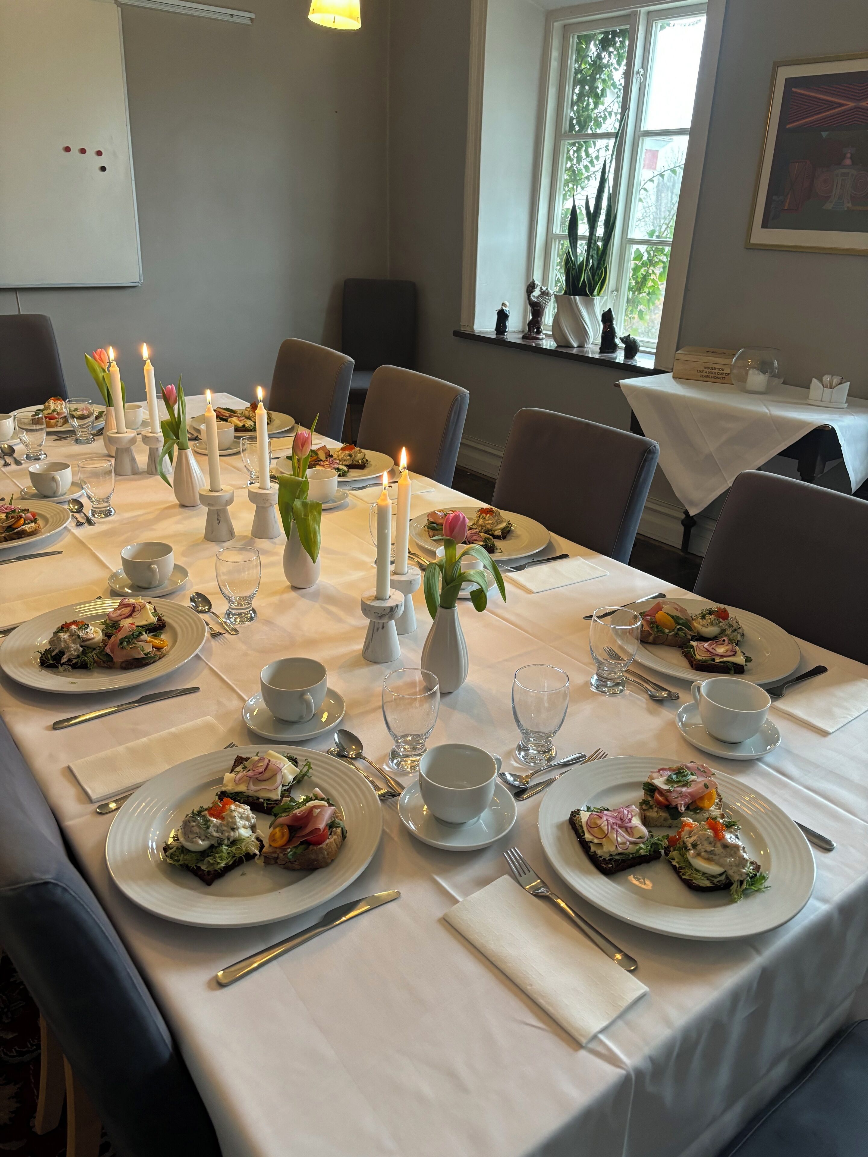A dining table set for a meal with candles, plates of food, and glassware.