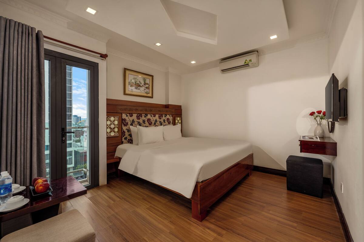 Une chambre d’hôtel avec un lit, un bureau et une chaise, une télévision et une fenêtre avec des rideaux.