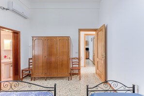 Cozy retreat with a bed, wardrobe, and chair, featuring a sink and door to a separate room.
