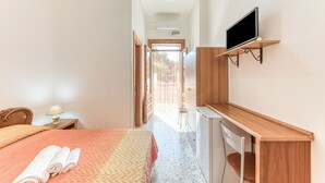A hotel room with a bed, a desk, a TV, and a window.