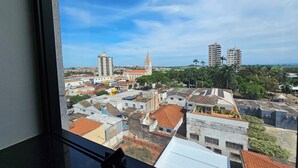 A cityscape viewed from a window, featuring a mix of historic and modern buildings, a prominent church, and a clear blue sky.