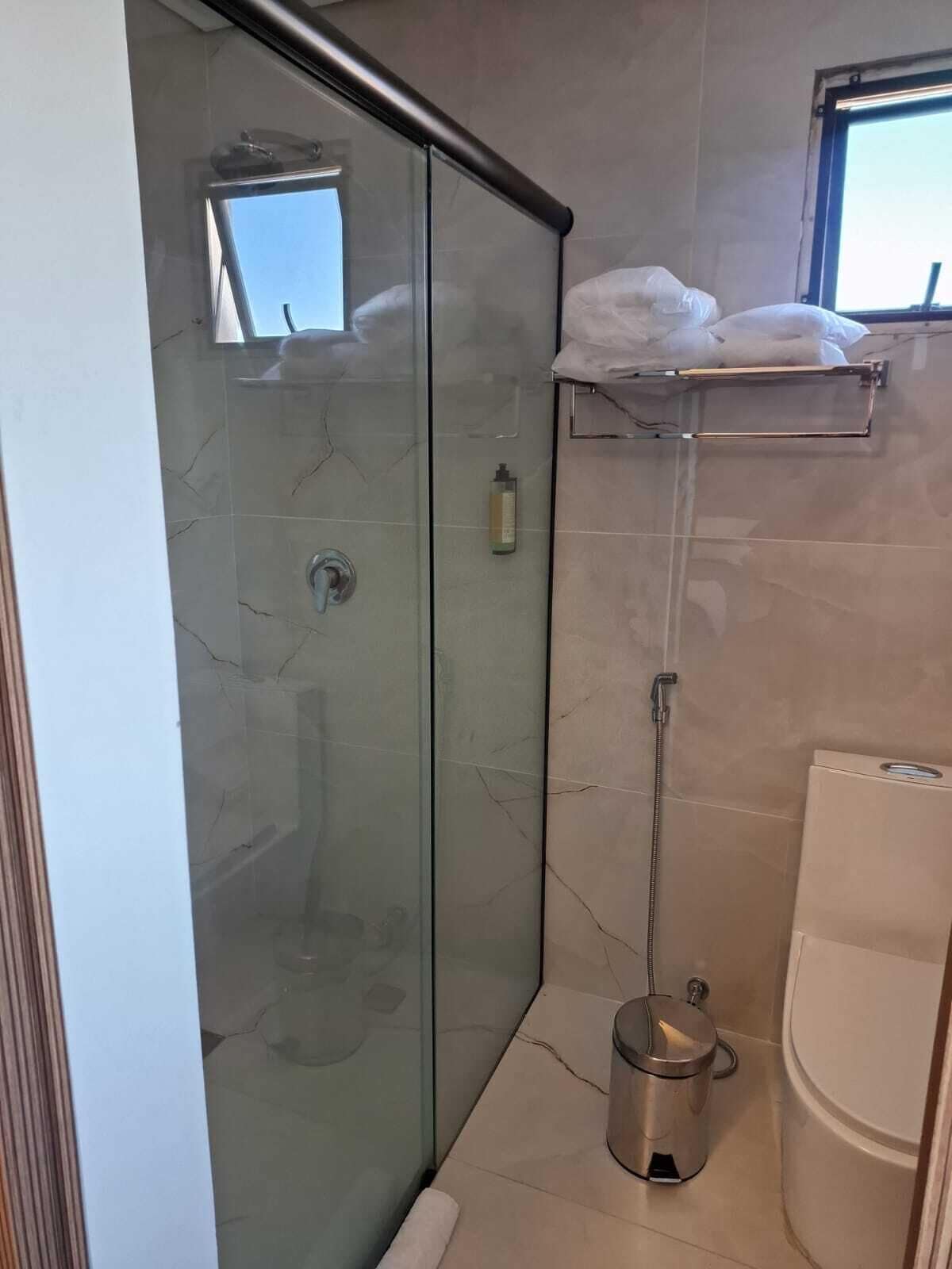 Eine Duschkabine mit Handbrause, ein Handtuchhalter und eine Toilette.