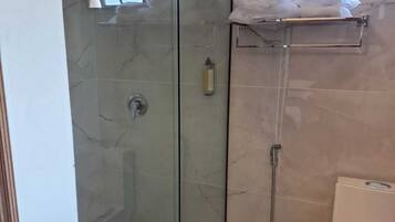 Eine Duschkabine mit Handbrause, ein Handtuchhalter und eine Toilette.
