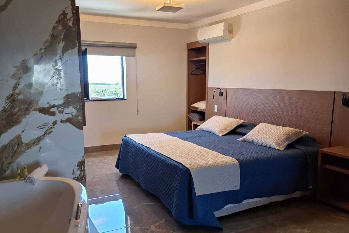 Een slaapkamer met een groot bed, een inbouwkast, een badkuip en een raam met uitzicht.