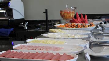 Ein reichhaltiges Buffet mit verschiedenen Speisen, darunter Aufschnitt, Obst und Gemüse.