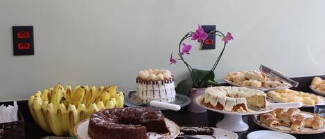 Ein reichhaltiges Buffet mit verschiedenen Desserts, darunter Kuchen und Gebäck, sowie einer Bananengruppe.