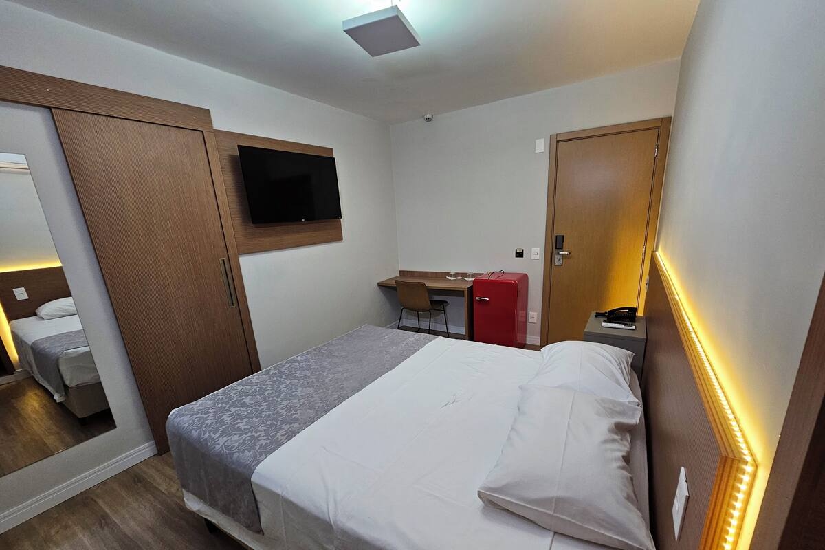 Een hotelkamer met een bed, een bureau, een televisie en een kledingkast.