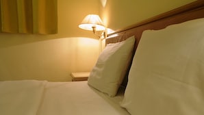 A neatly made bed with white linens and pillows, a bedside table, and a lamp. - Hotel O Hotel Ramai (Sandakan)