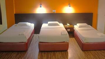 A hotel room with two single beds, a wooden floor, and two wall-mounted lights.