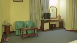 A room with a green sofa, a small wooden table, a TV, and a desk with a mirror. - Hotel O Hotel Ramai (Sandakan)
