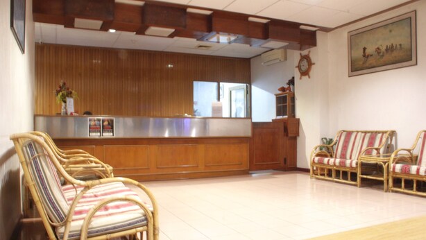 A reception area with a wooden reception desk, wicker chairs, and a sofa. - Hotel O Hotel Ramai (Sandakan)