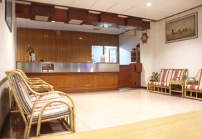 Zona de recepción con mostrador de madera, sillas de mimbre y un sofá.