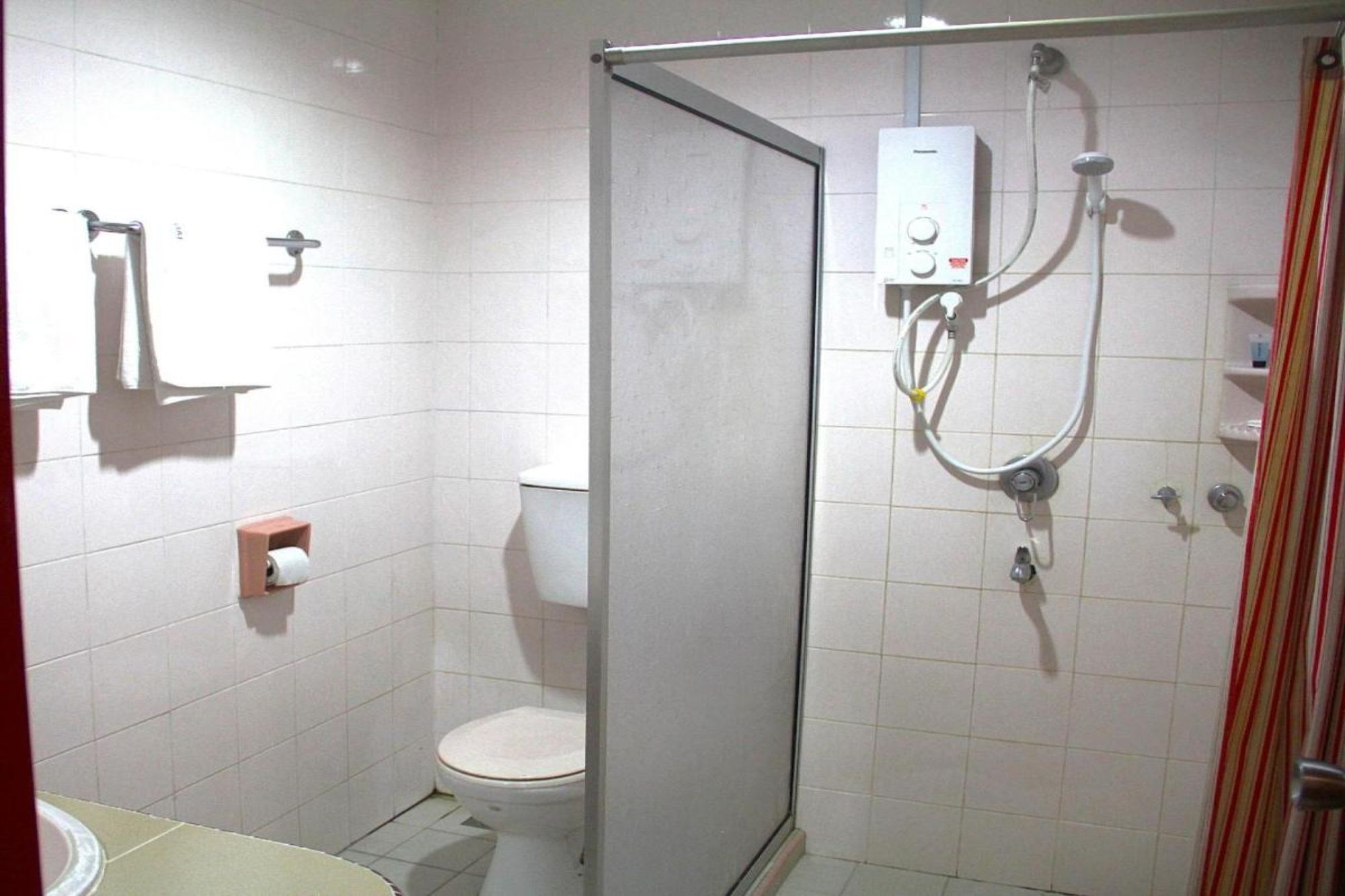 Een badkamer met toilet, douchecabine en handdoekhouder.