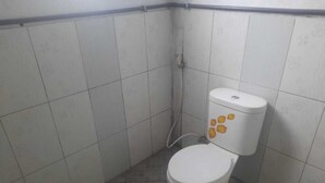A small, tiled bathroom with a toilet and a shower. - Hotel O Home Stay Syariah Annur (Jalaksana)
