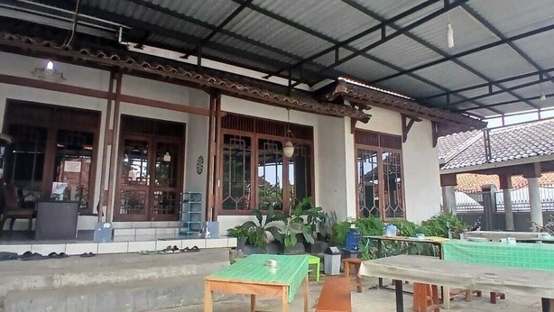 A traditional building with a covered porch, wooden tables, and potted plants. - Hotel O Home Stay Syariah Annur (Jalaksana)