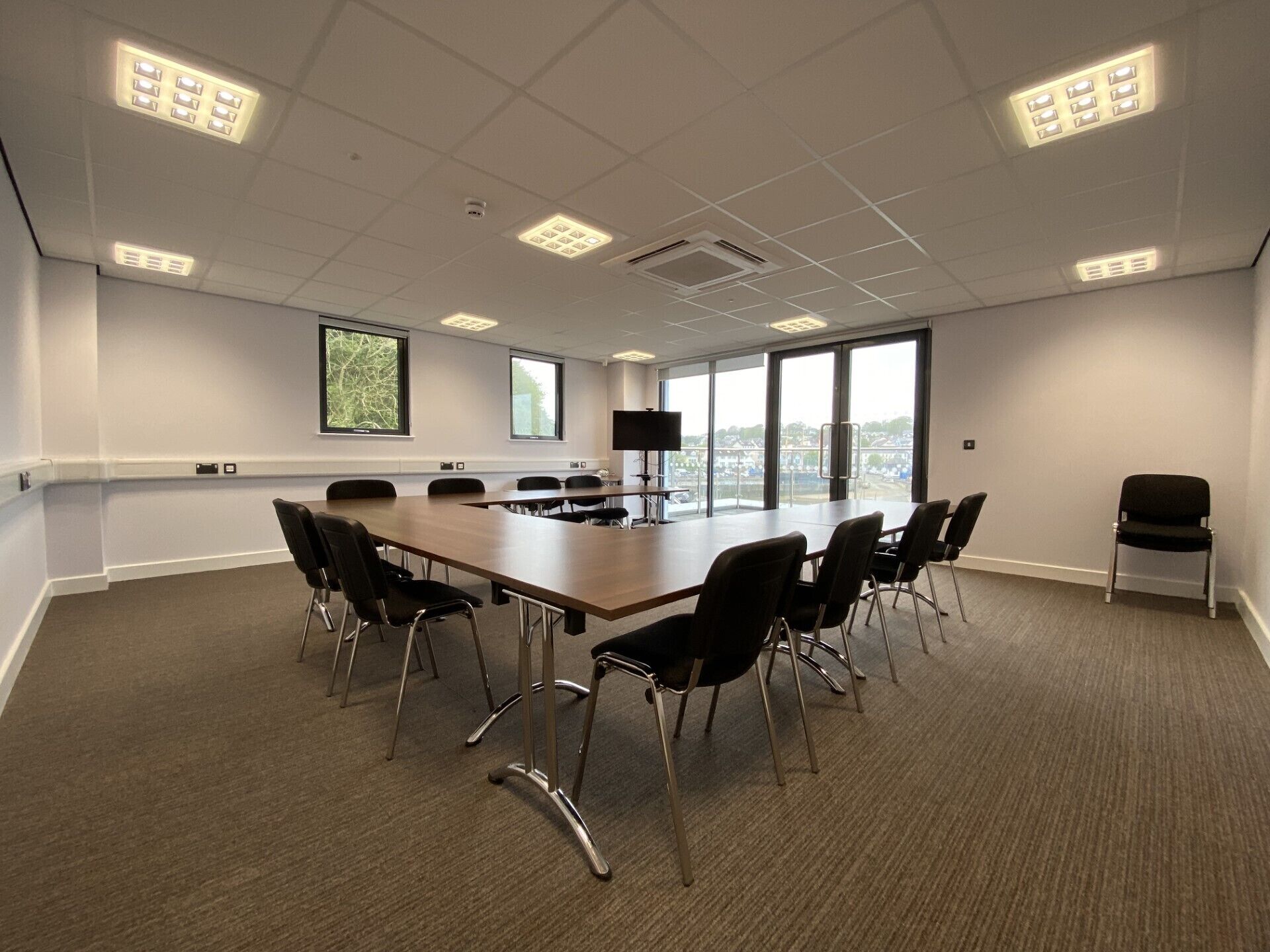 A conference room with a long table, chairs, a TV, and large windows with a view.