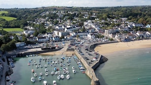 A coastal town with a marina filled with boats, a sandy beach, and residential buildings. - Harbour Stays - The Marine Centre (Saundersfoot)