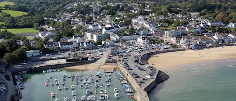A coastal town with a marina filled with boats, a sandy beach, and residential buildings.
