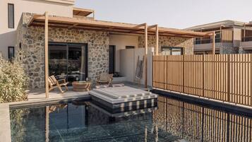 A modern outdoor pool area with stone walls, wooden pergola, and lounge chairs.