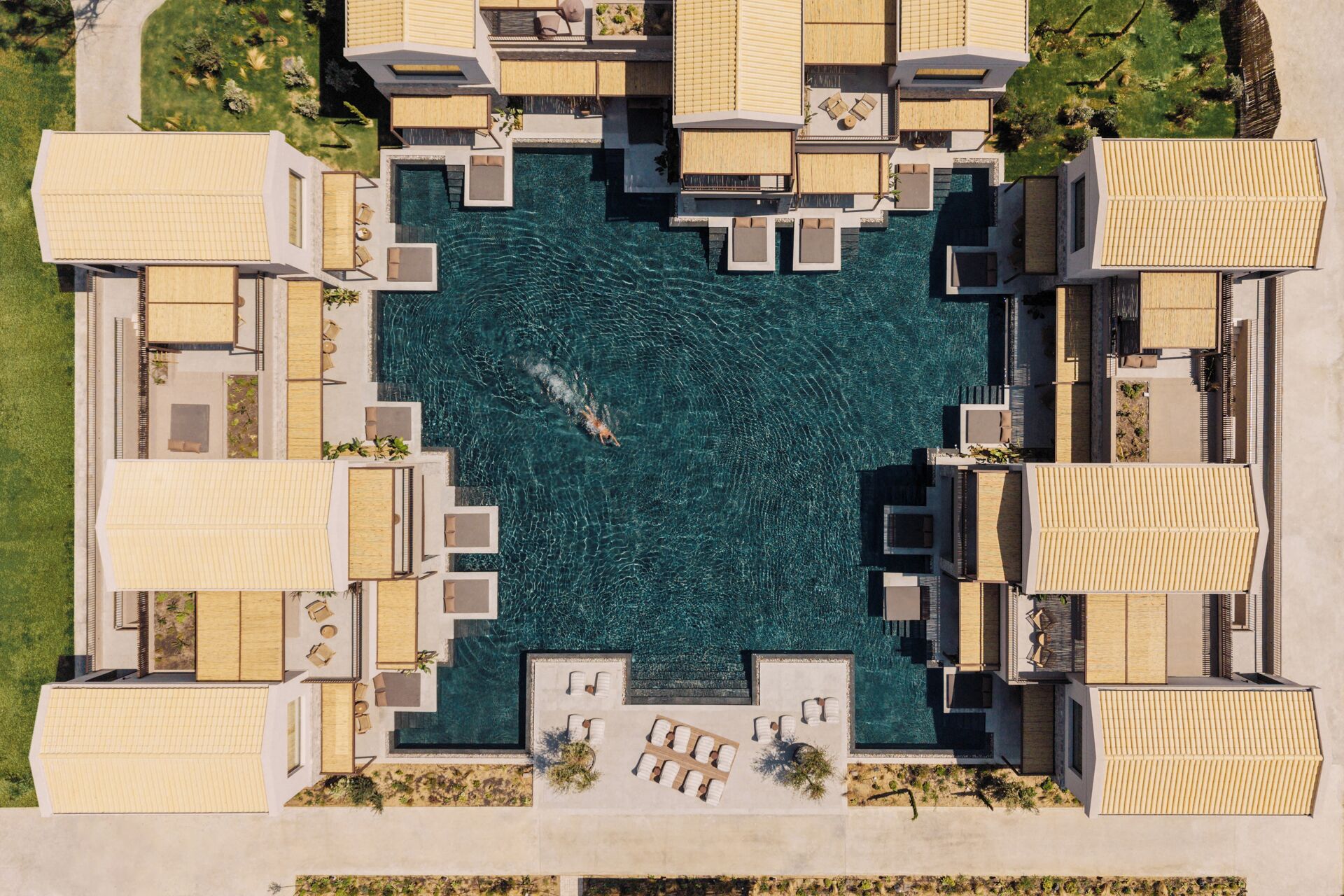 A modern resort with a central swimming pool surrounded by multiple guest rooms with balconies.
