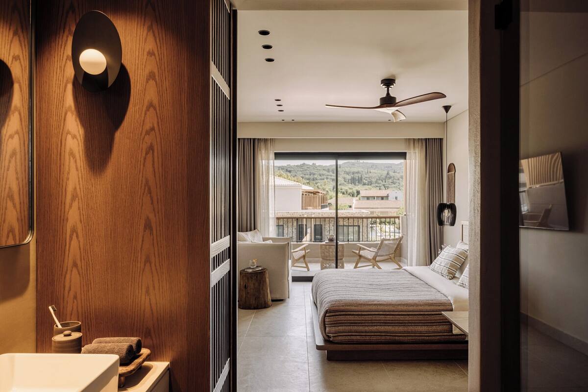 Una camera da letto moderna con un letto grande, un balcone vista edifici, una ventola a soffitto e una parete in legno.