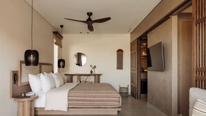 A bedroom with a bed, bedside tables, a desk, a mirror, a ceiling fan, and a TV.