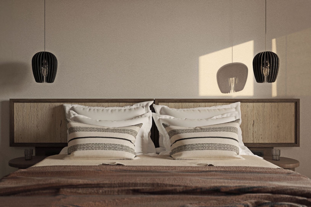 A bed with a wooden headboard, two pillows, and a striped blanket.
