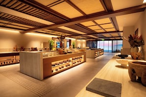 Un hall d’hôtel moderne avec un îlot central, des poutres en bois et une grande fenêtre offrant une vue panoramique.