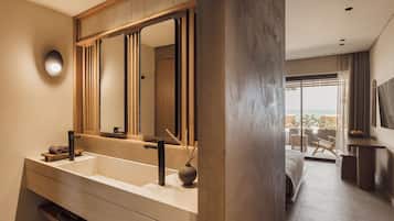 Un baño moderno con un espejo grande, lavamanos dobles y vistas a un balcón con mobiliario exterior.