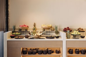 A buffet with various fruits and bowls of food.