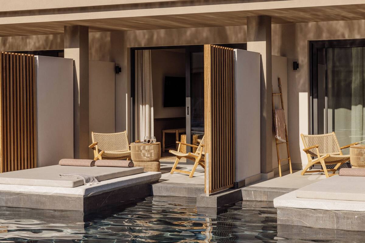 Area piscina con lettini, un tavolino e una scaletta di legno.