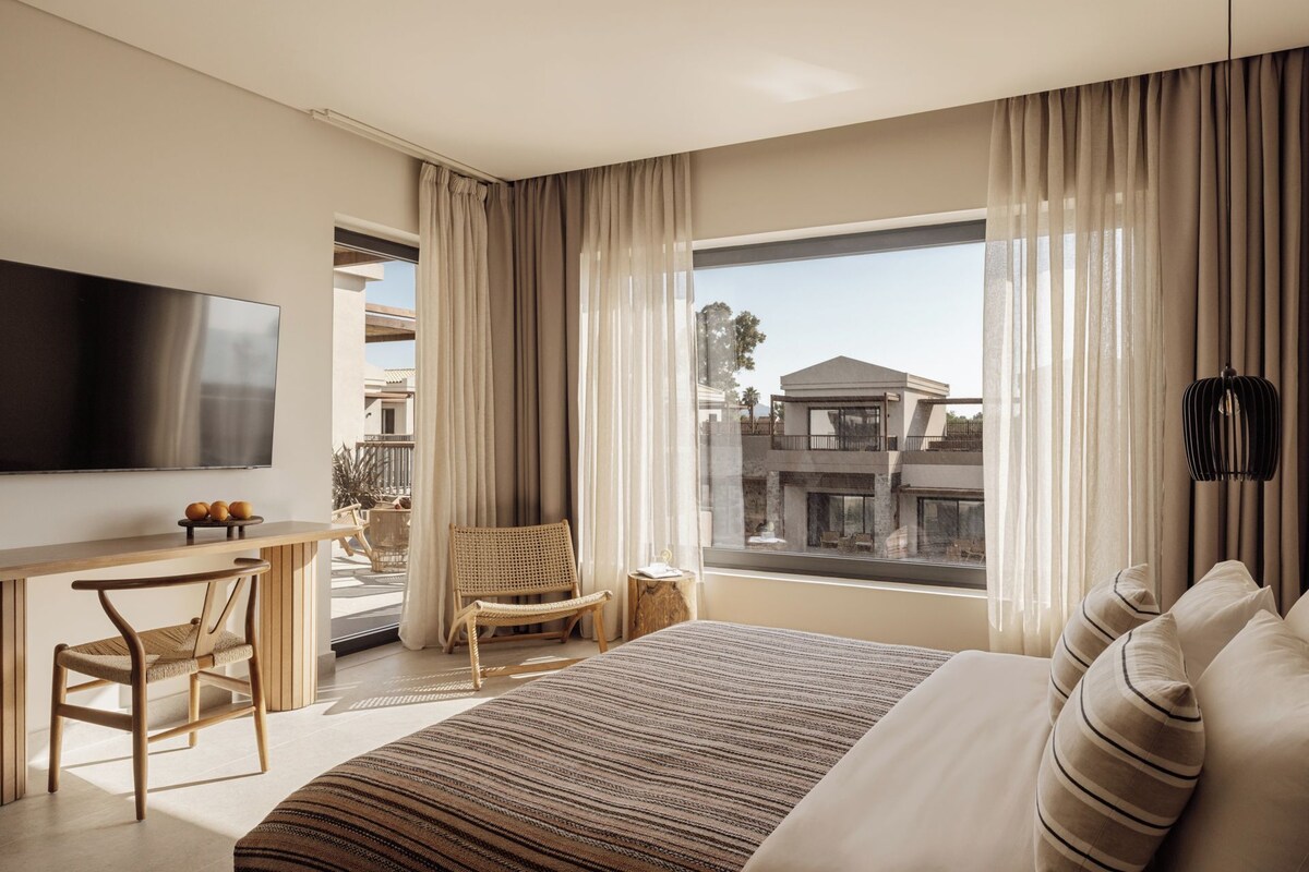 Een moderne hotelkamer met een groot bed, een flatscreen televisie, een bureau en een stoel.