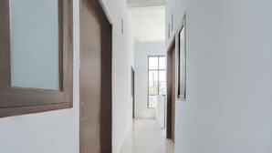 Un pasillo con puerta de madera, una ventana y acceso a un balcón.
