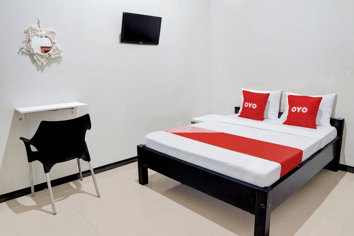 Un dormitorio ordenado con cama, escritorio y silla.