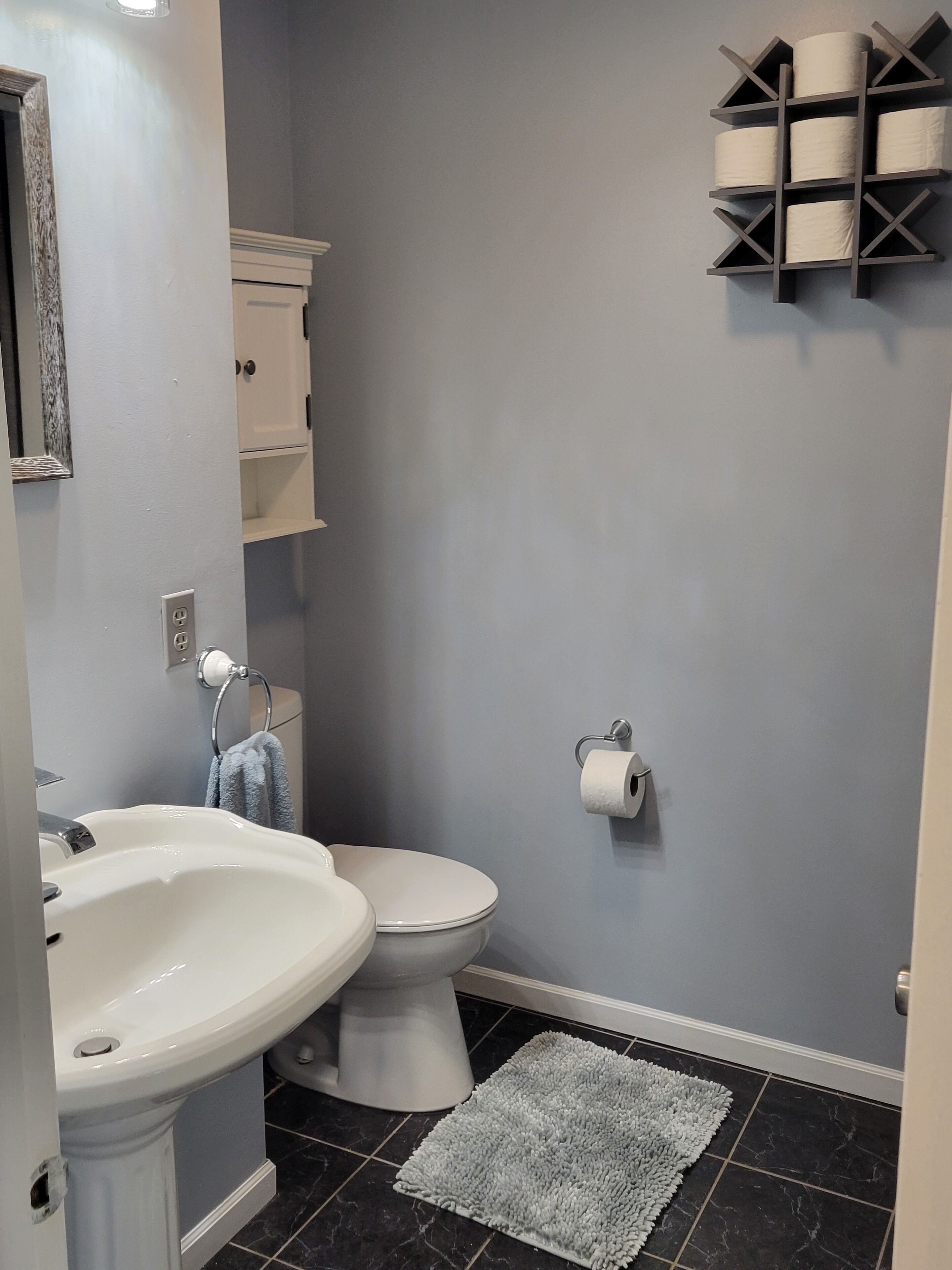 Un baño con lavamanos blanco, inodoro y perchero para toallas.