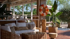 A wicker sofa with cushions, a glass-top coffee table, and a potted plant. - September Hotel Thessaloniki (Pylaia-Chortiatis)