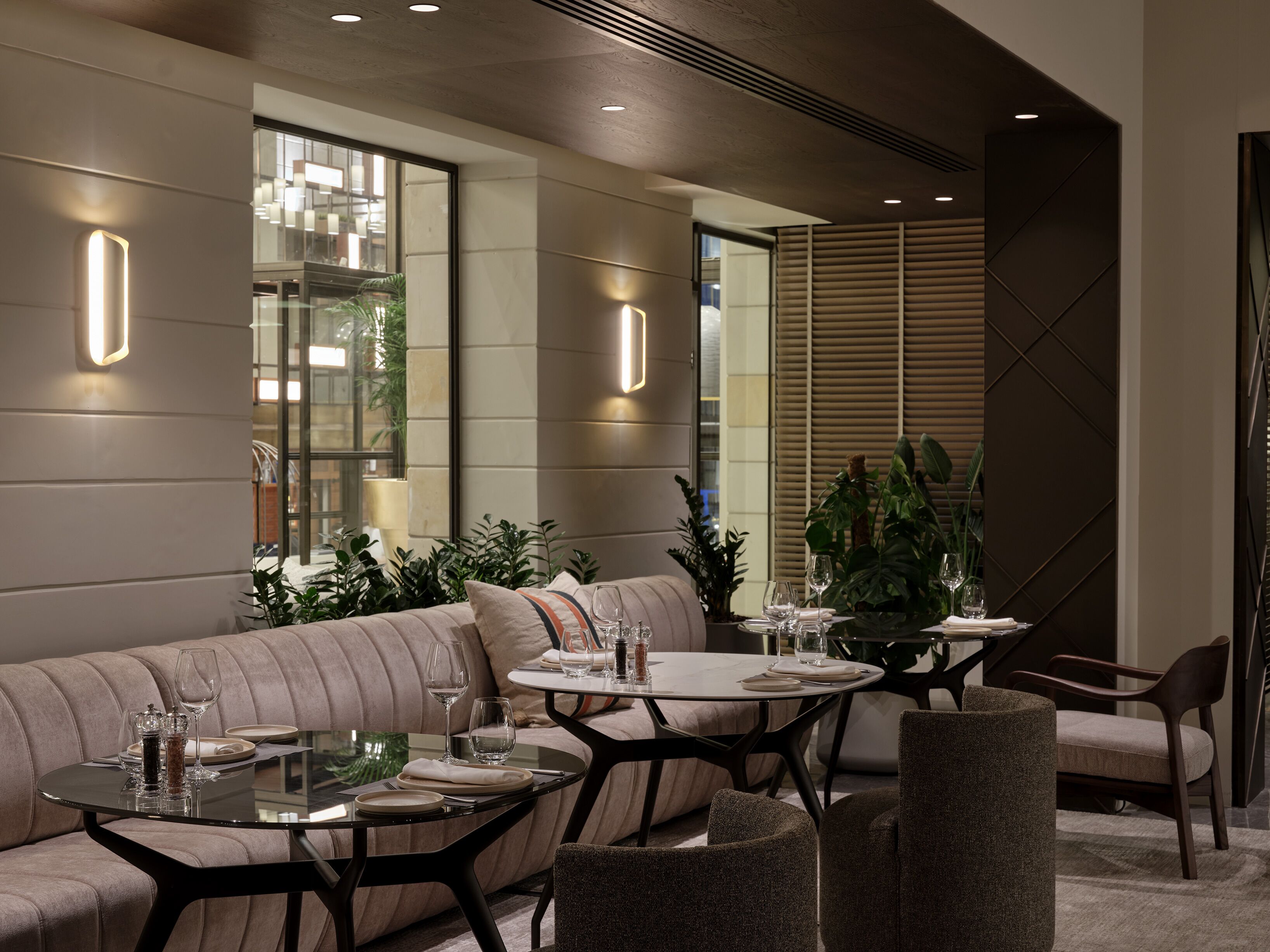 A modern dining area with a sofa, round tables, and chairs.